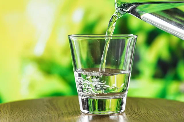 bicchiere acqua purificata nelle mani di una giovane ragazza