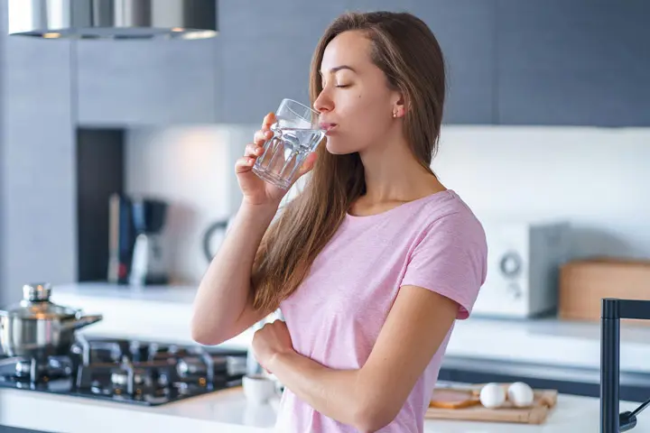 ragazza che beve acqua purificata da rubinetto